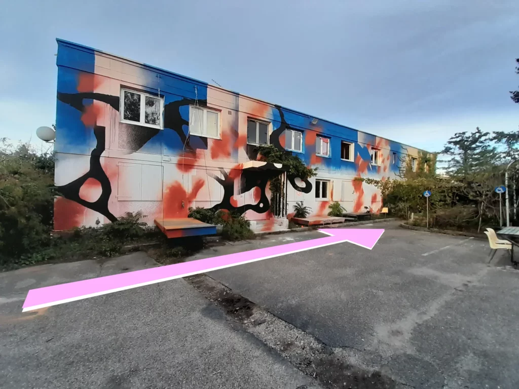 Vue de la cour extérieure. L'entrée se trouve au fond à droite de la façade peinte.