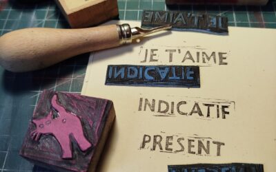 Une photo de matériel de linogravue avec imprimé sur une feuille à l'encre: "je t'aime, indicatif présent".